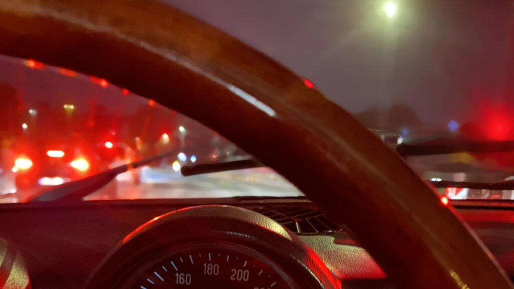Blick aus dem Cockpit eines Oldtimers auf die Straßenlichter in der Dunkelheit